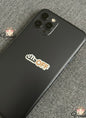Black smartphone with 'Mute Off' sticker on a gray textured surface