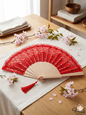 Elegant red lace folding hand fan with a wooden frame and red tassel, displayed on a table with cherry blossoms.