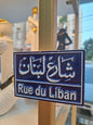 Street sign for 'Rue du Liban' with Arabic text on a blue background