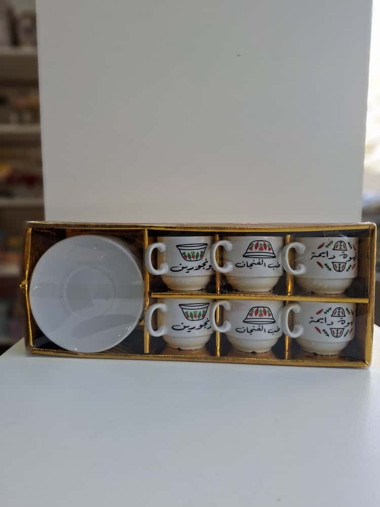 Set of six white cups with Arabic text in a decorative box on a white surface.