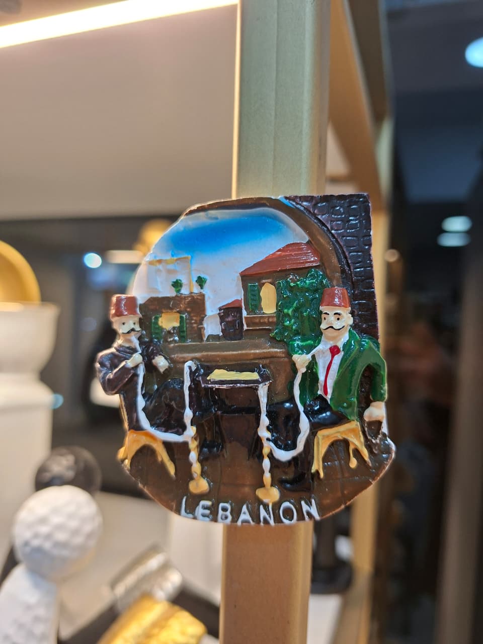 Decorative item with two figures and the word 'Lebanon' on a blurred background