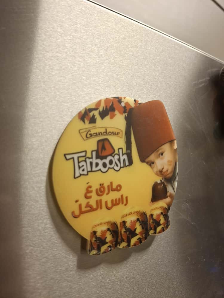 Tatboosh branding on a round sticker with a child wearing a fez hat.