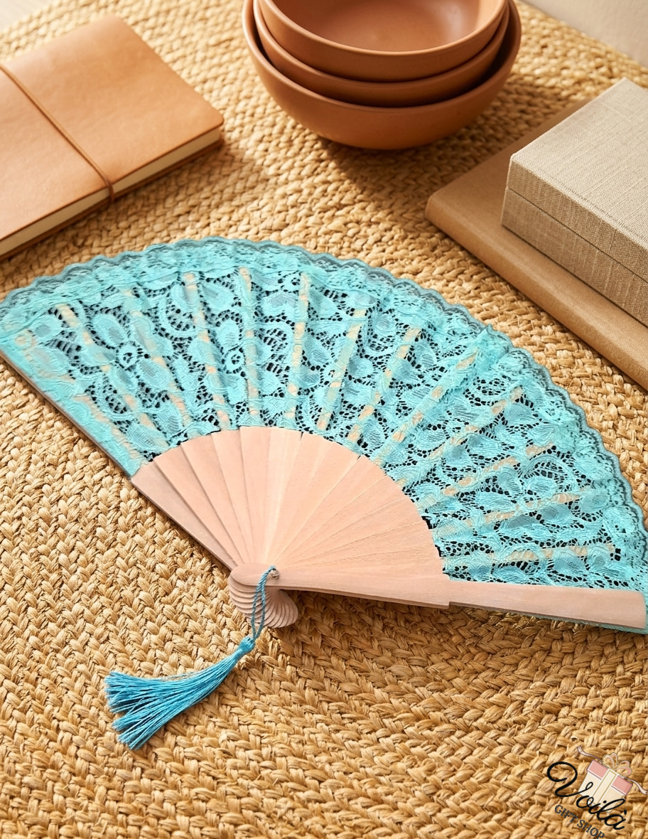 Elegant turquoise lace hand fan with natural wooden ribs and a matching tassel on a woven mat