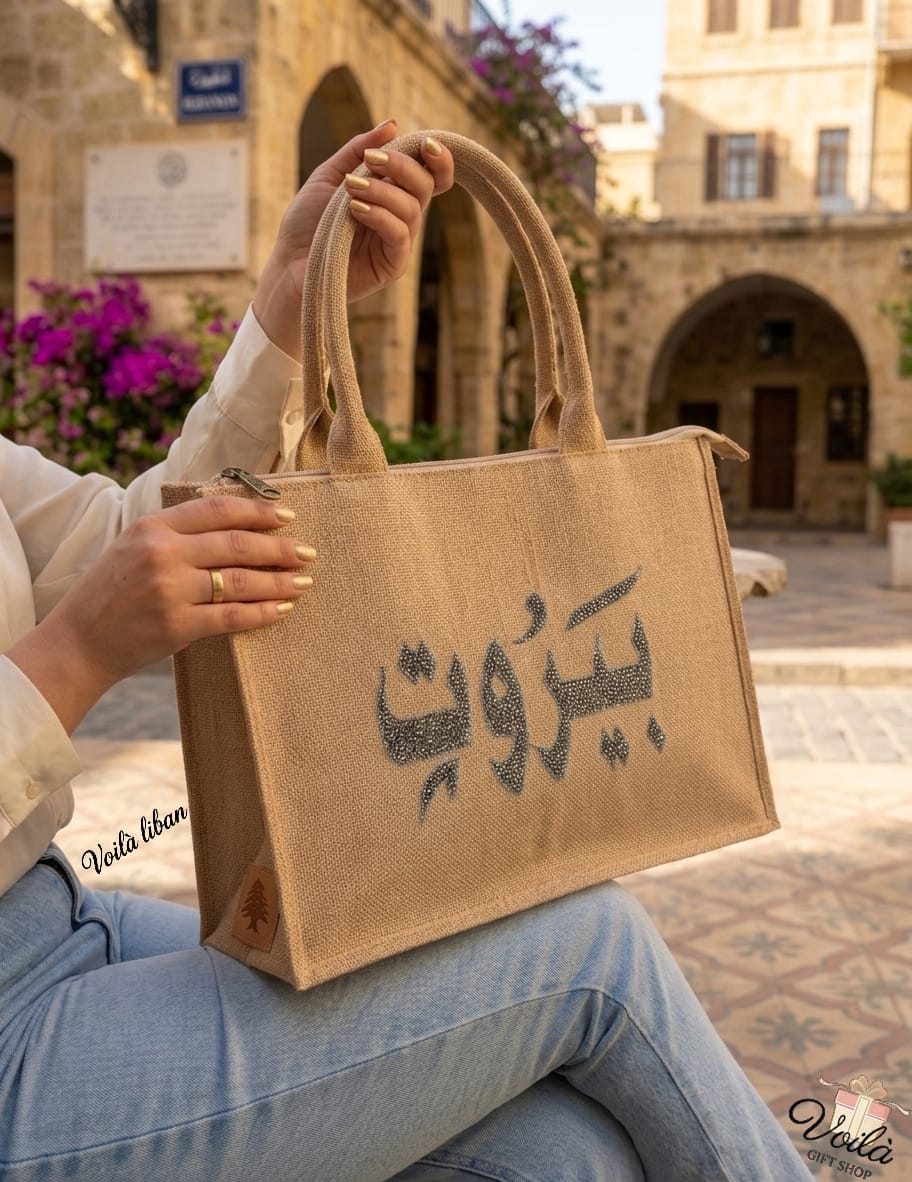Premium natural jute tote bag featuring black crystal Beirut Arabic calligraphy and a classic Lebanese cedar tree tag.