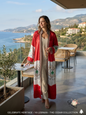 A woman wearing the red and white Ya Lebnan Heritage Cedar Abaya overlooking the beautiful Lebanese coast